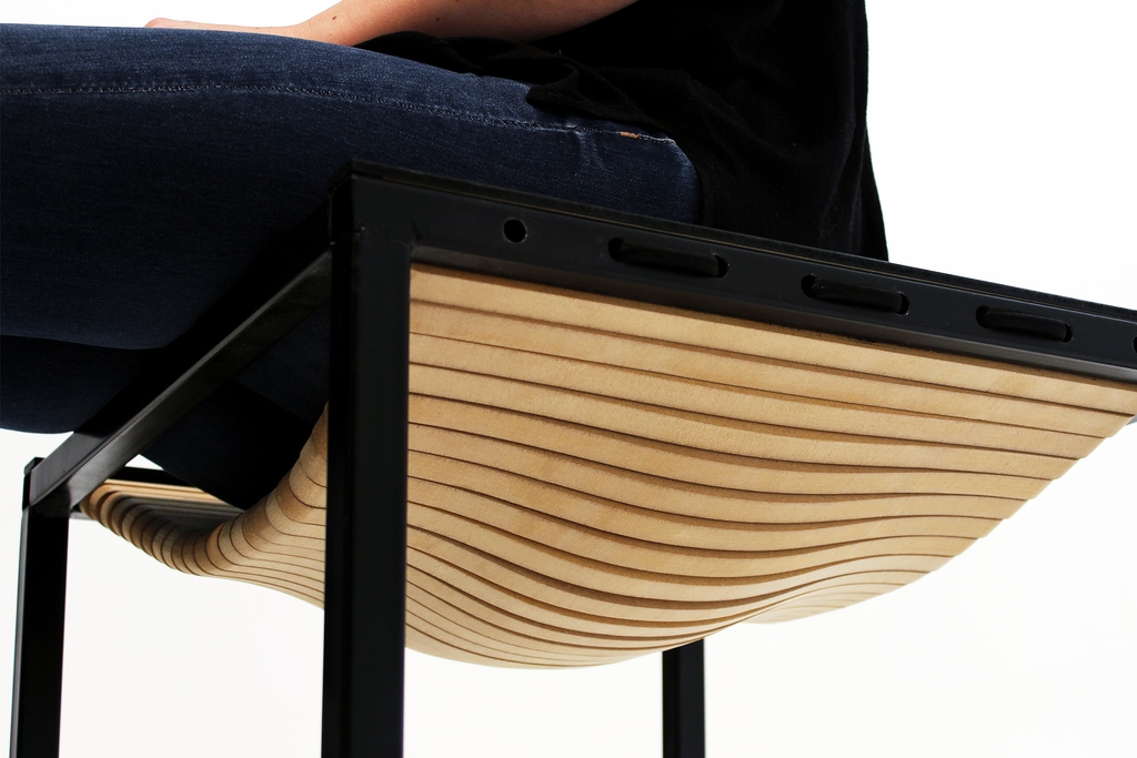 Person sitting on physical prototype of multi-purpose table, showing the surface becoming flexible.